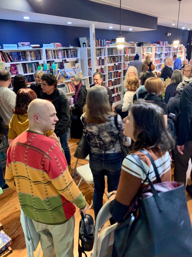 Pic of a full house at Roscoe Books, with audience socializing.